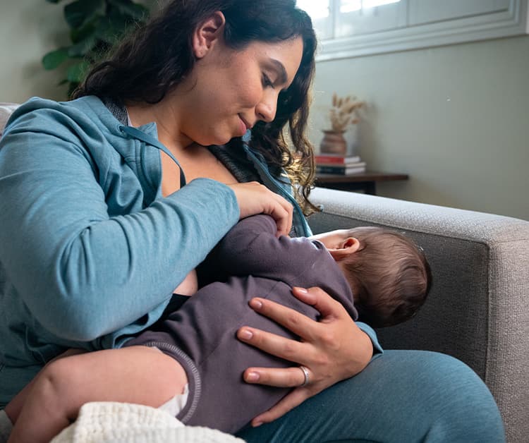 Smiling mother breastfeeding baby in a position to prevent acid reflux.