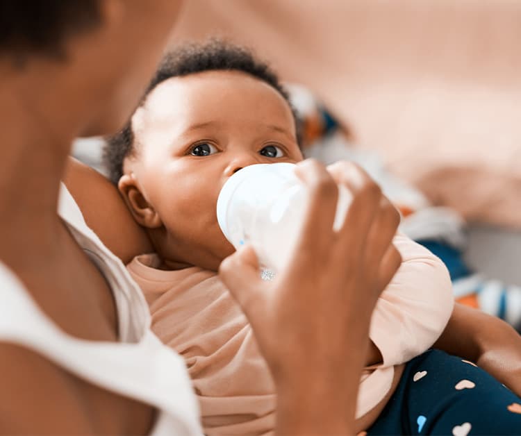 Mom holding her daughter as baby drinks a bottle