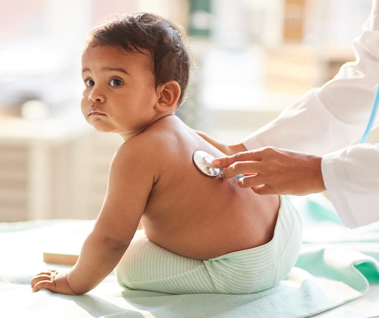 Pediatra escuchando los pulmones del bebé feliz