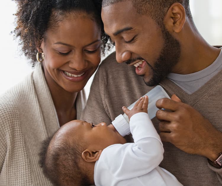 New dad and mom bottle feeding their baby