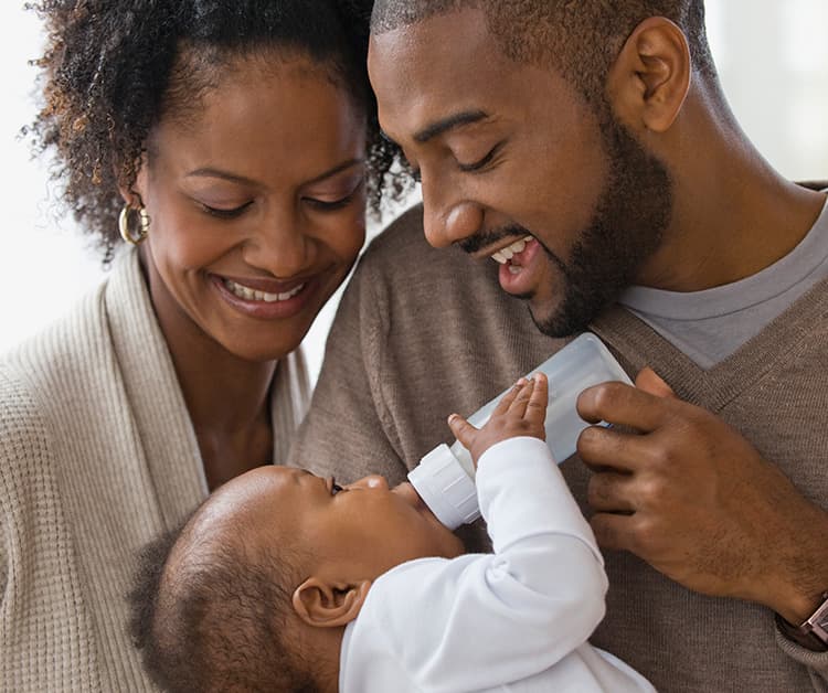 Mom bottle feeding her baby who is looking up at her
