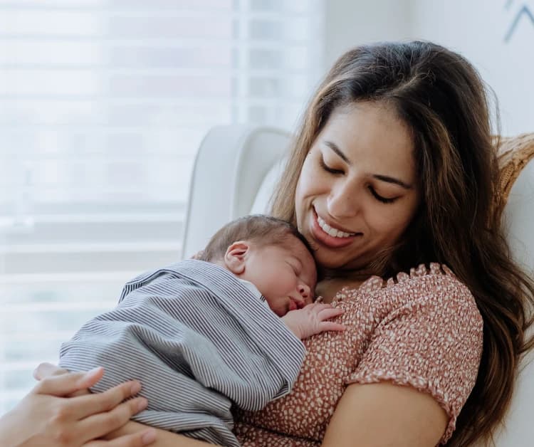 Mom sitting in a chair and holding a sleeping baby