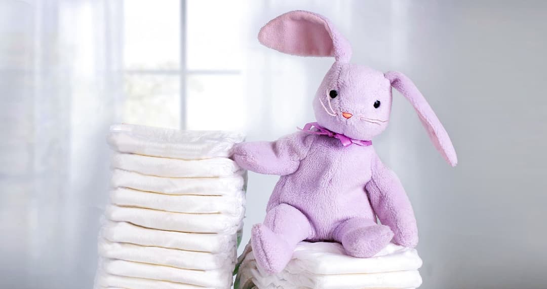 Purple bunny sitting on a stack of diapers next to a tub of NeuroPro Gentlease