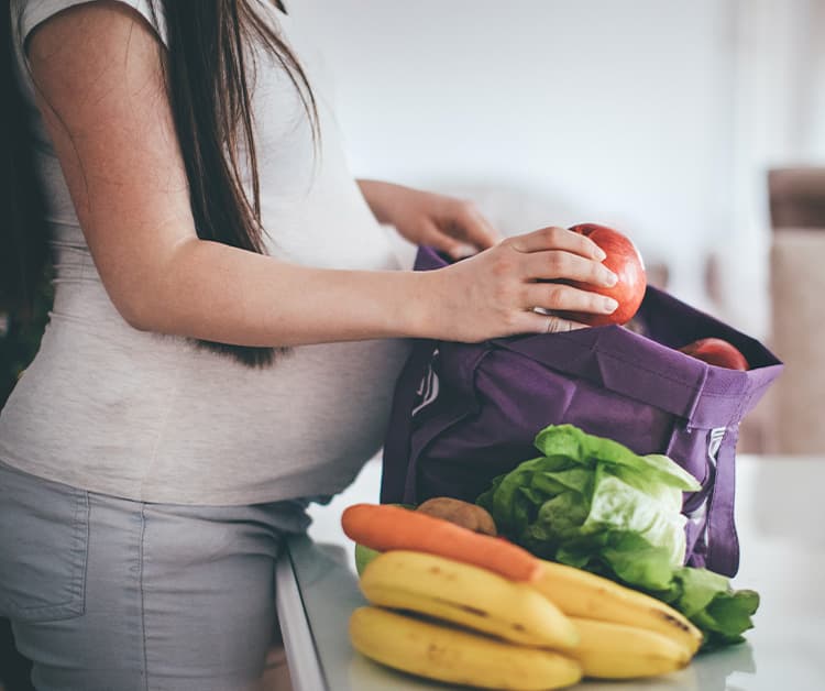 Expecting mom unpacking her grocery bag