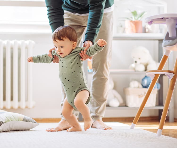 Parent helping infant learn to walk