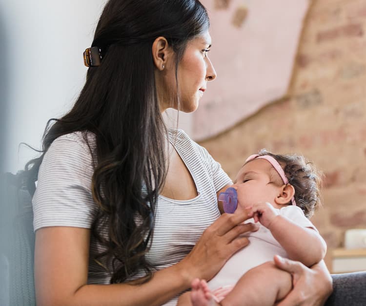 New mother holding newborn while looking out the window