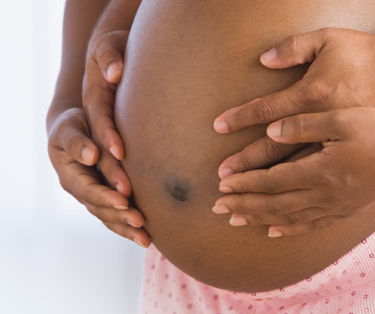 Pregnant woman and spouse's hands holding her belly