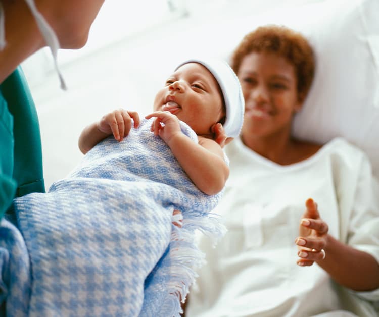 Nurse handing baby to new mom
