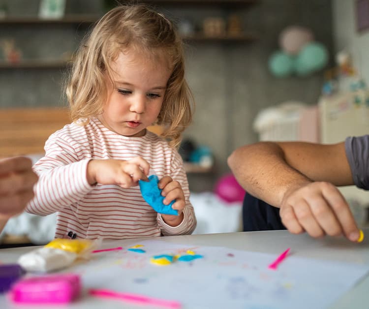 Toddler girl and her dad playing with play-dough