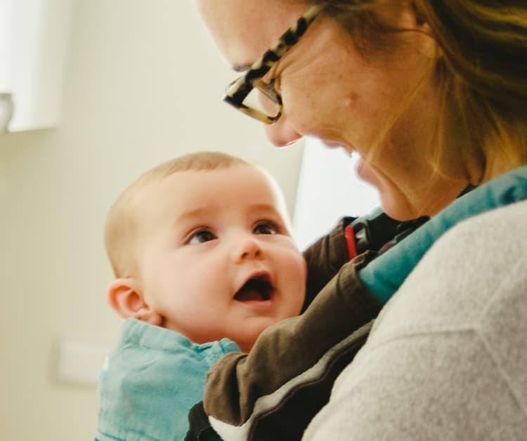 Smiling mom holding happy baby in a carrier