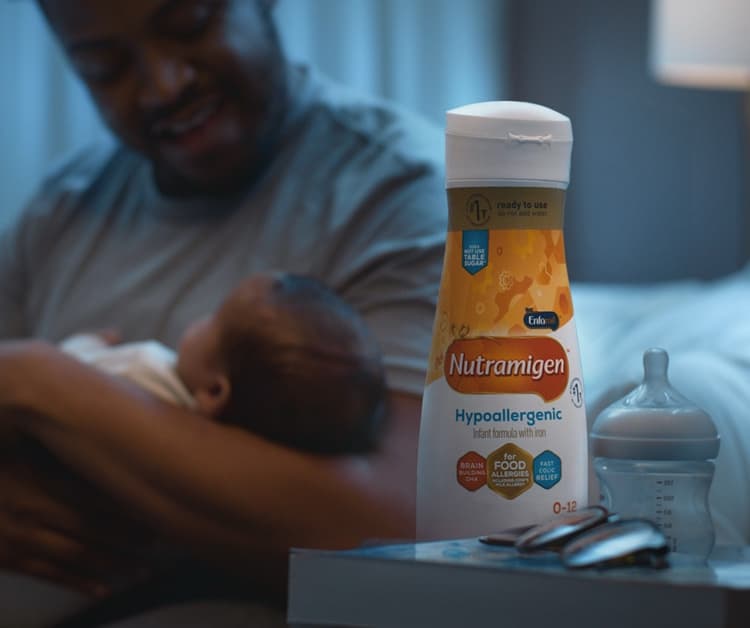 Parent joyfully lifting baby in sunlit outdoor setting