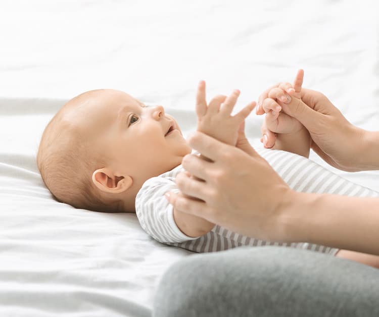 Baby laying on their back as mom holds their hands