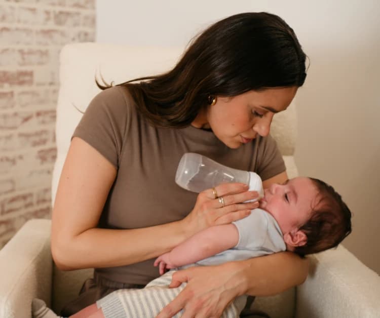 Mamá mece al bebé y le da el biberón.