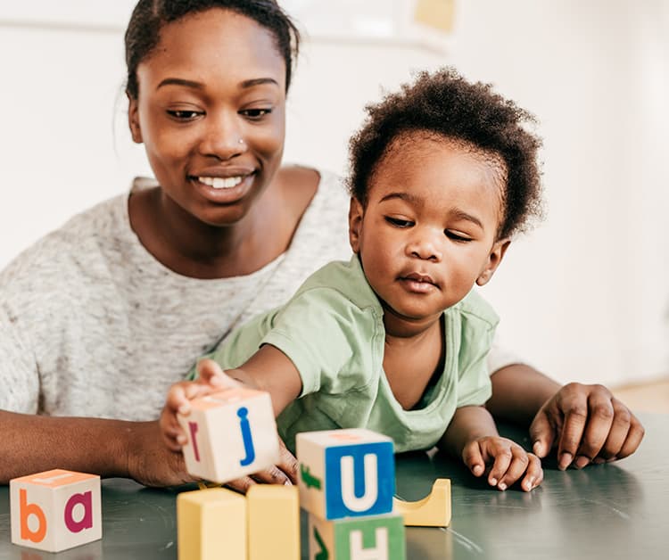 Mamá y niño jugando con bloques con letras