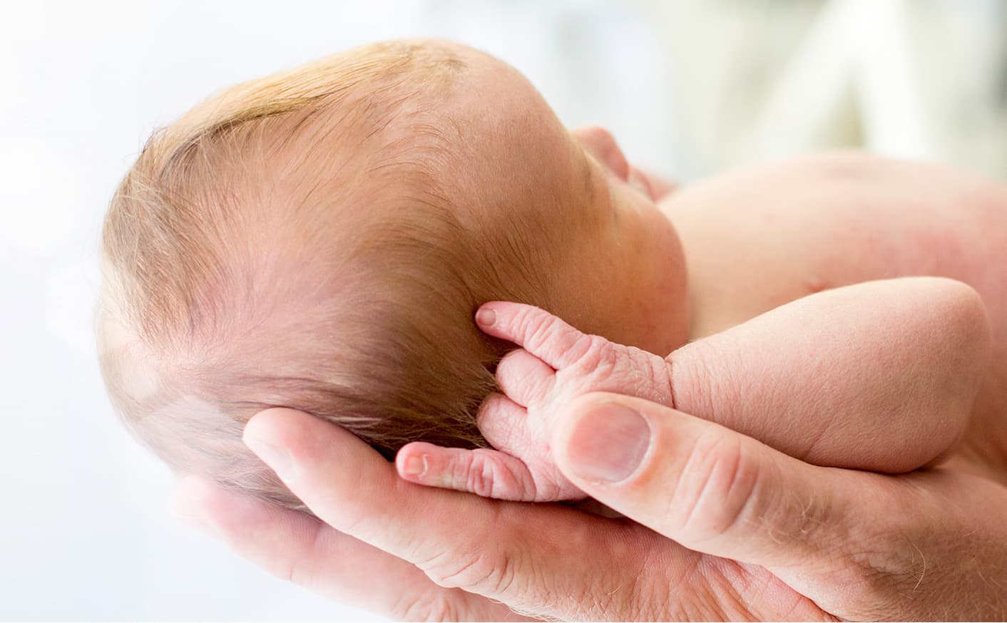 Parent Holding Newborn In Hands