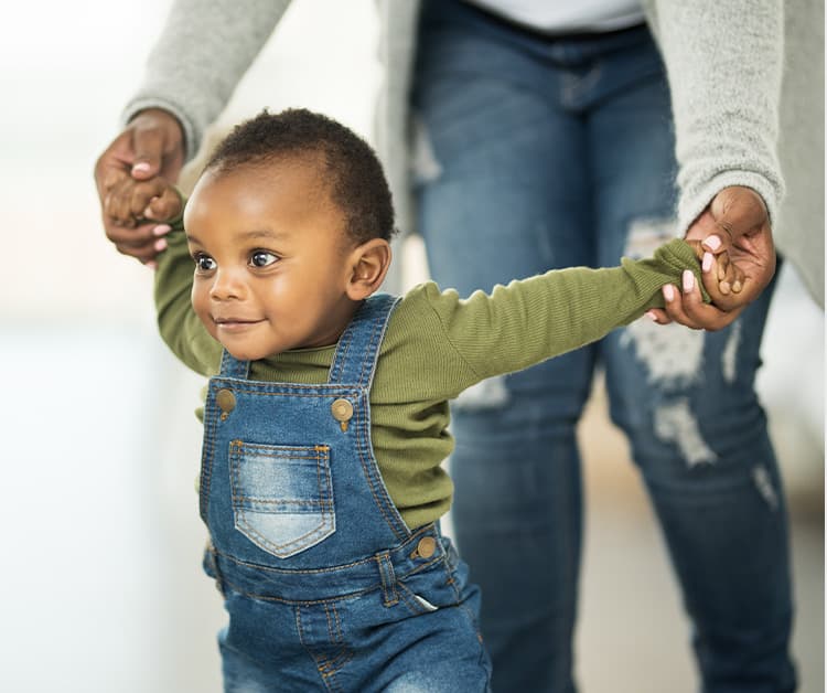 Niño caminando y tomado de la mano de mamá
